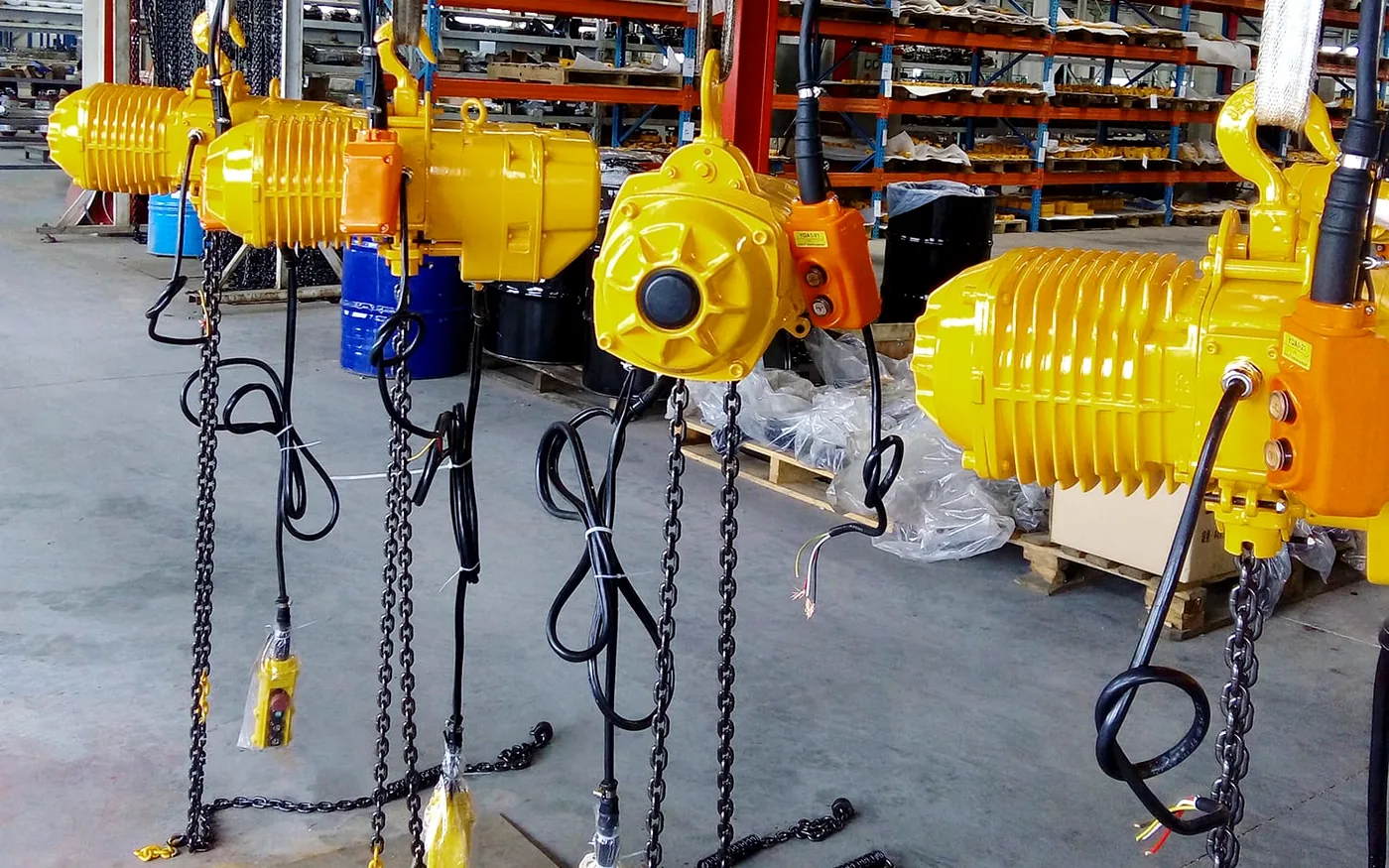 Yellow electric hoists arranged in a workshop for lifting equipment supply preparation